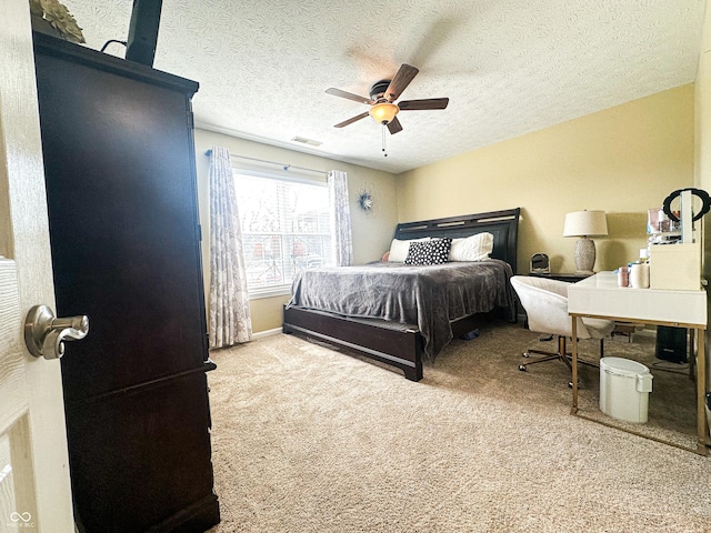 bedroom featuring a textured ceiling, carpet floors, visible vents, and a ceiling fan