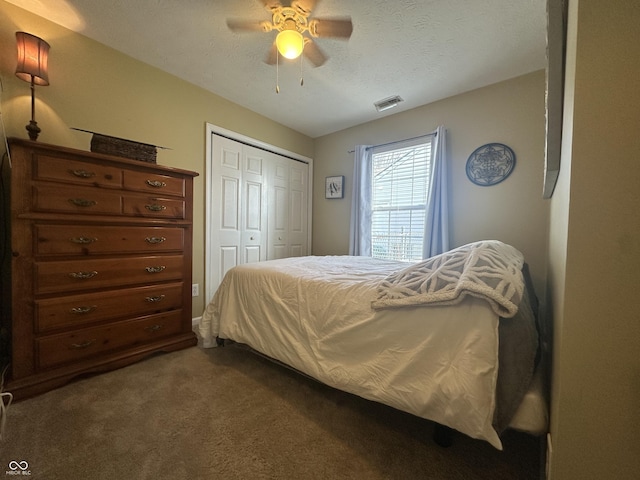 bedroom with visible vents, ceiling fan, a textured ceiling, dark carpet, and a closet