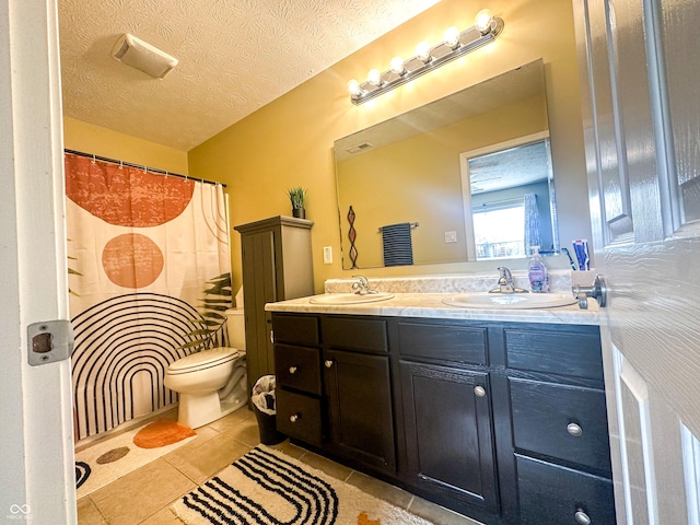 full bath with toilet, double vanity, a sink, and tile patterned floors