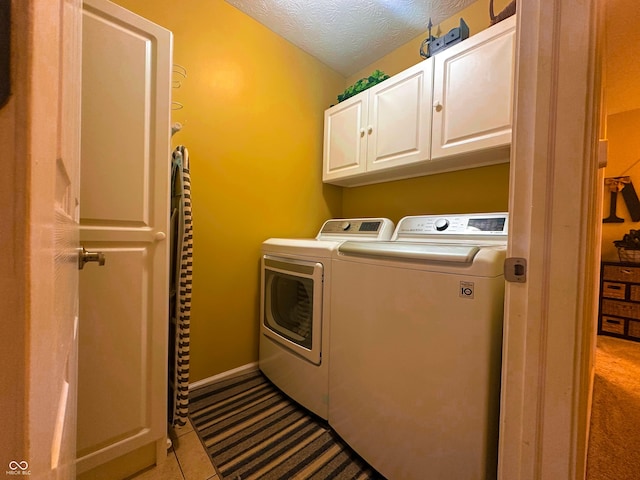 washroom with baseboards, cabinet space, a textured ceiling, and washing machine and clothes dryer