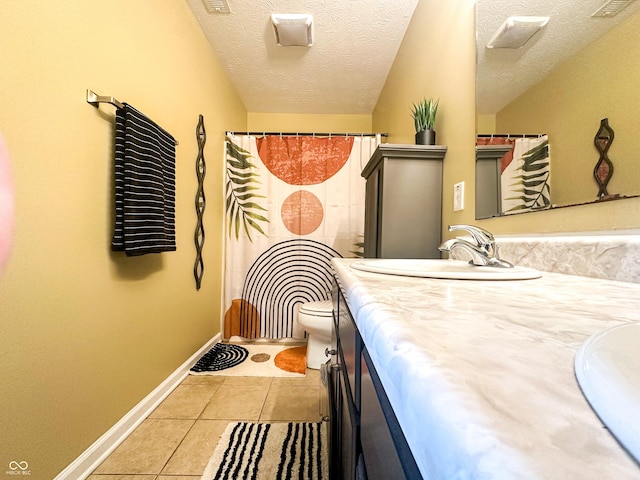 interior space with baseboards, toilet, tile patterned floors, a textured ceiling, and vanity