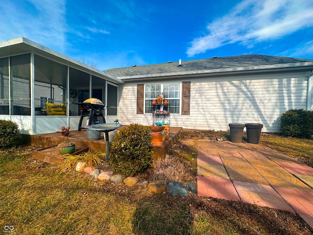 rear view of house featuring a patio, roof with shingles, and a sunroom