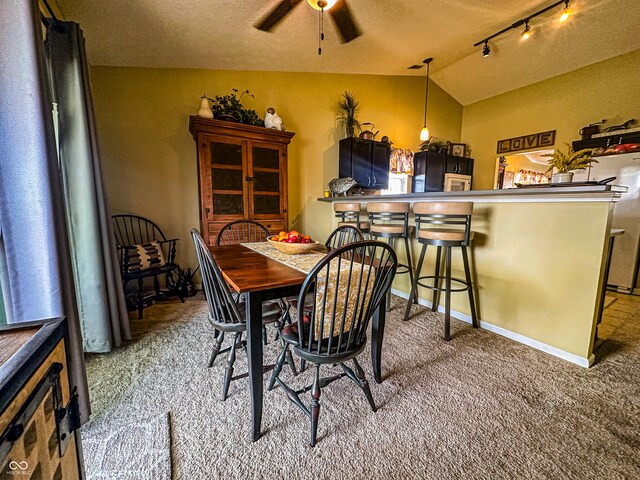 carpeted dining room with baseboards, ceiling fan, vaulted ceiling, a textured ceiling, and track lighting