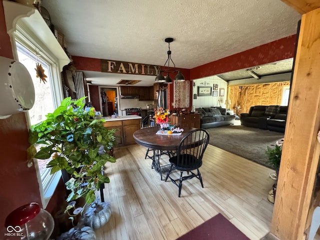 dining space with light hardwood / wood-style floors and a textured ceiling