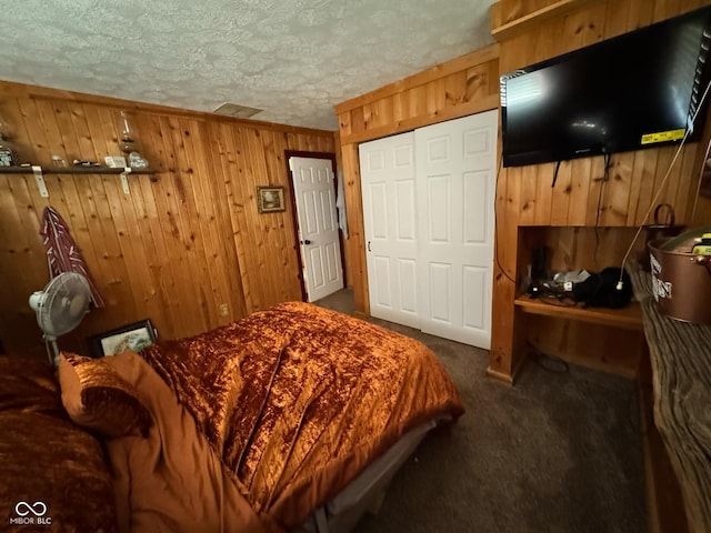 carpeted bedroom with wooden walls, a closet, and a textured ceiling