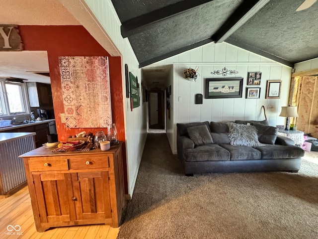 living room featuring a textured ceiling, light hardwood / wood-style flooring, and vaulted ceiling with beams