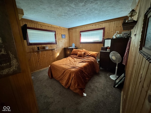 bedroom featuring wood walls, carpet, and a textured ceiling