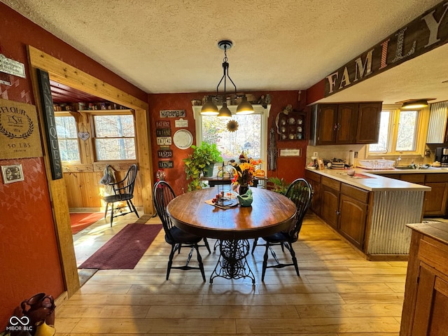 dining room with light hardwood / wood-style flooring, a notable chandelier, and a textured ceiling