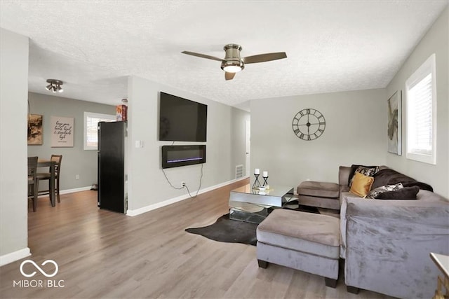 living room with a textured ceiling, hardwood / wood-style floors, and ceiling fan