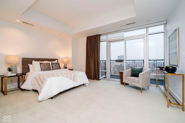 bedroom featuring access to exterior, carpet, a raised ceiling, and expansive windows