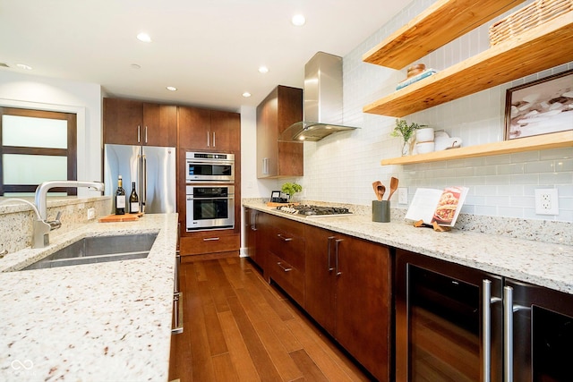 kitchen featuring decorative backsplash, appliances with stainless steel finishes, sink, and wall chimney range hood