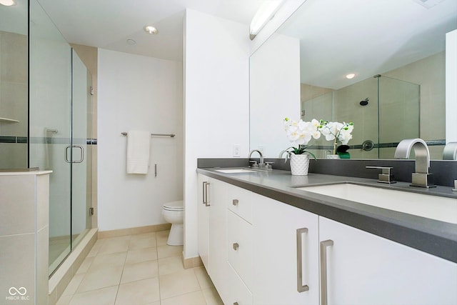 bathroom with tile patterned floors, vanity, toilet, and a shower with shower door