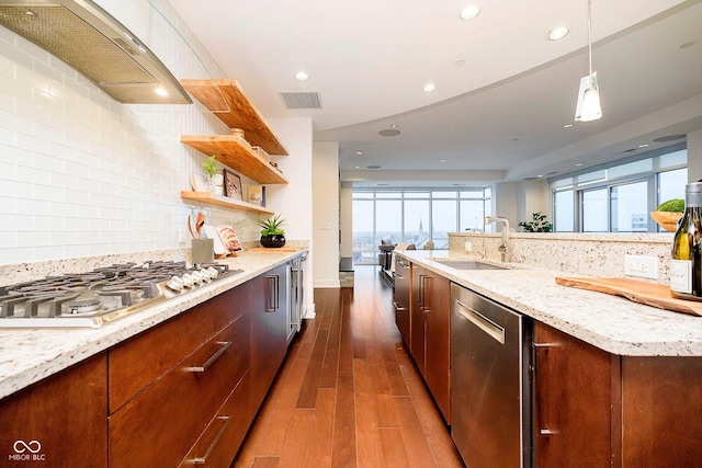 kitchen with dark wood-type flooring, sink, wall chimney exhaust hood, light stone counters, and stainless steel appliances