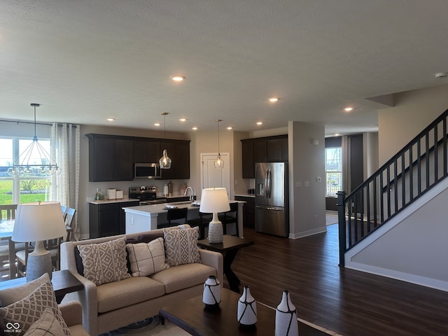 living room featuring a chandelier, a textured ceiling, sink, and dark hardwood / wood-style flooring