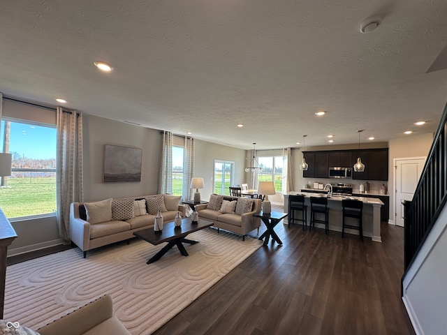 living room featuring a wealth of natural light, a textured ceiling, and dark hardwood / wood-style flooring