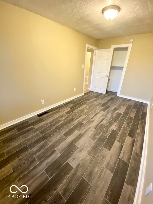 unfurnished bedroom featuring dark wood-type flooring and a textured ceiling