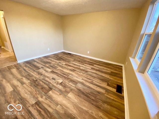 unfurnished room featuring wood-type flooring and a textured ceiling