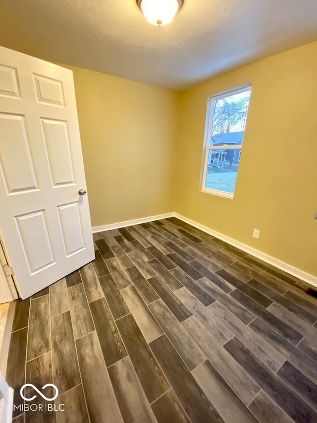 spare room featuring dark hardwood / wood-style floors and a textured ceiling