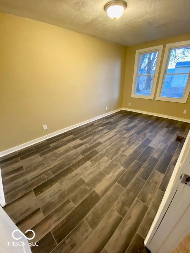 empty room featuring dark hardwood / wood-style floors and a textured ceiling