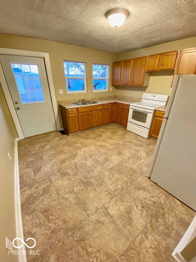 kitchen with white appliances, sink, and a textured ceiling