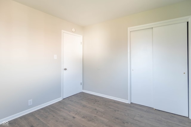 unfurnished bedroom with dark wood-type flooring and a closet