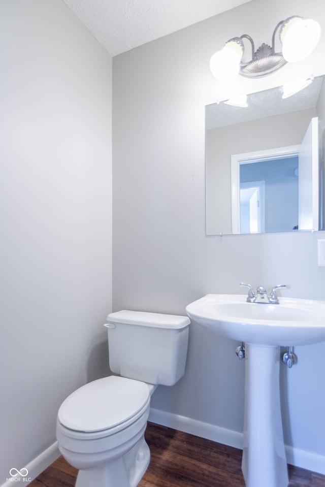 bathroom with a textured ceiling, toilet, and hardwood / wood-style floors