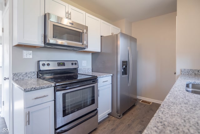 kitchen with sink, dark wood-type flooring, appliances with stainless steel finishes, white cabinets, and light stone counters