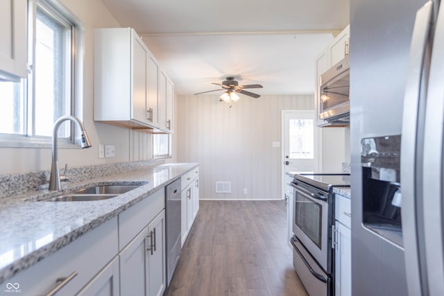 kitchen with light stone countertops, sink, white cabinets, and stainless steel appliances