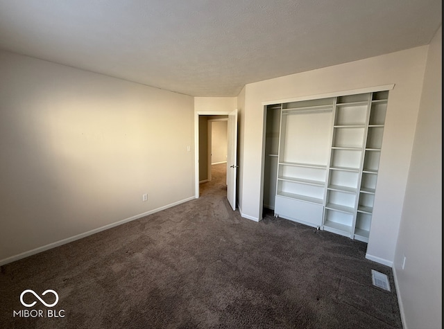 unfurnished bedroom with a closet and dark colored carpet