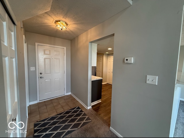 foyer with dark tile patterned flooring and a textured ceiling