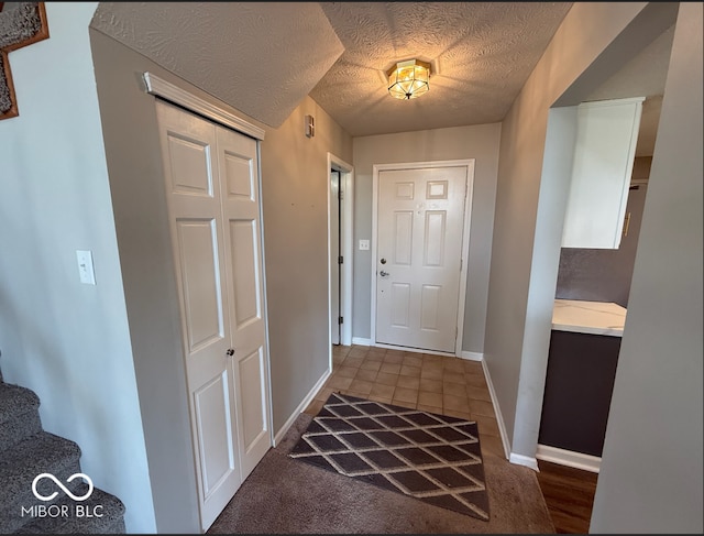 doorway to outside with dark tile patterned flooring and a textured ceiling