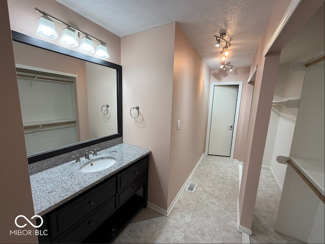 bathroom featuring vanity, a textured ceiling, and track lighting