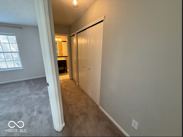 hall with carpet floors and a textured ceiling