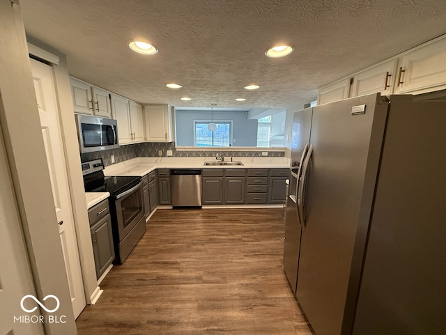 kitchen with decorative backsplash, appliances with stainless steel finishes, a textured ceiling, wood-type flooring, and white cabinets