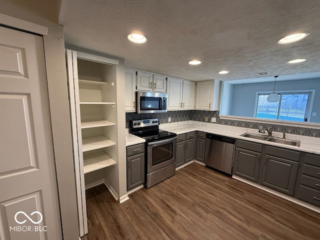 kitchen featuring appliances with stainless steel finishes, tasteful backsplash, sink, pendant lighting, and white cabinetry