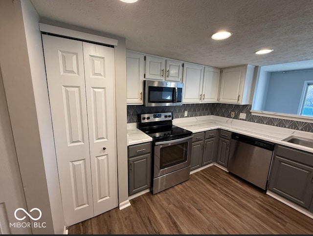 kitchen featuring a textured ceiling, stainless steel appliances, gray cabinets, and dark hardwood / wood-style floors