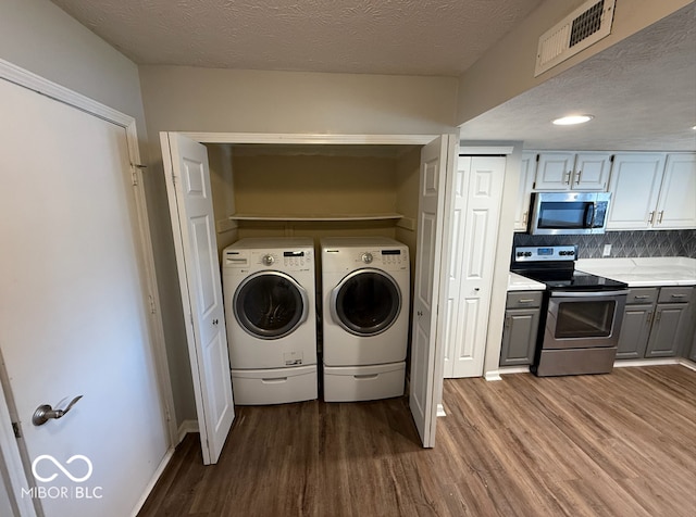 laundry room with separate washer and dryer, hardwood / wood-style floors, and a textured ceiling