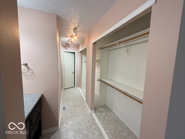 bathroom with a textured ceiling, vanity, and rail lighting