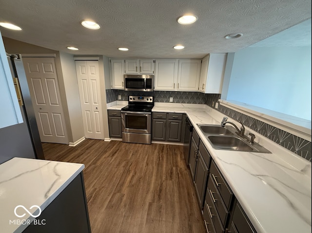 kitchen with a textured ceiling, sink, stainless steel appliances, and dark hardwood / wood-style floors