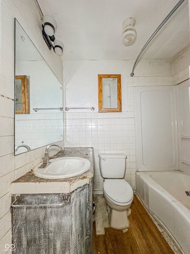 full bathroom with tile walls, wood-type flooring, vanity, shower / bathing tub combination, and toilet