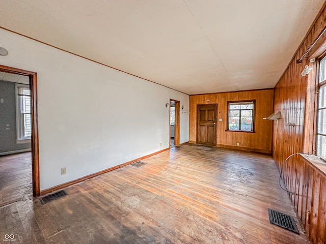 unfurnished room featuring wooden walls and hardwood / wood-style flooring