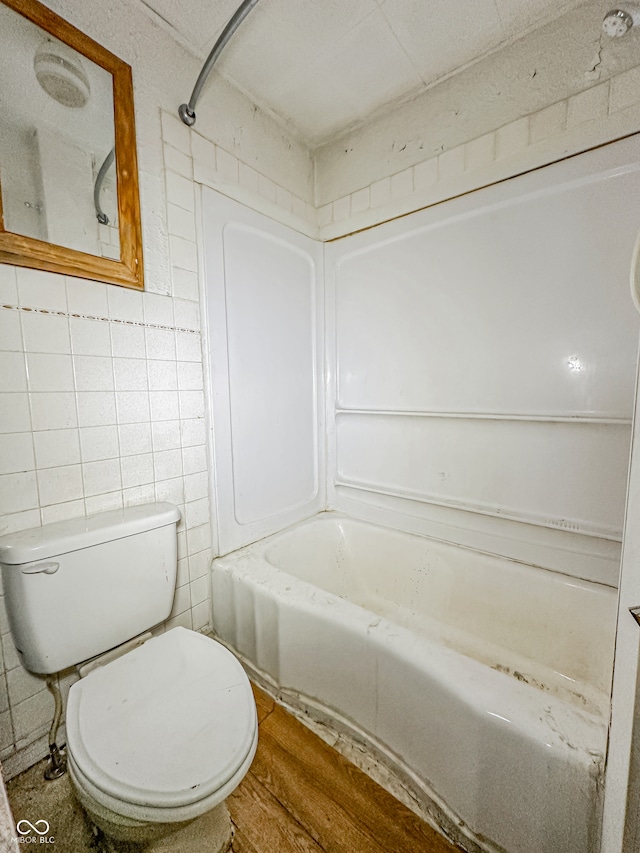 bathroom with hardwood / wood-style floors, toilet, shower / bathing tub combination, and tile walls