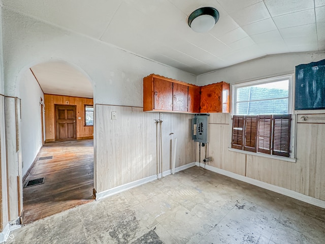 spare room with electric panel, wooden walls, light wood-type flooring, and vaulted ceiling