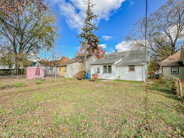 rear view of house with a yard and a storage shed