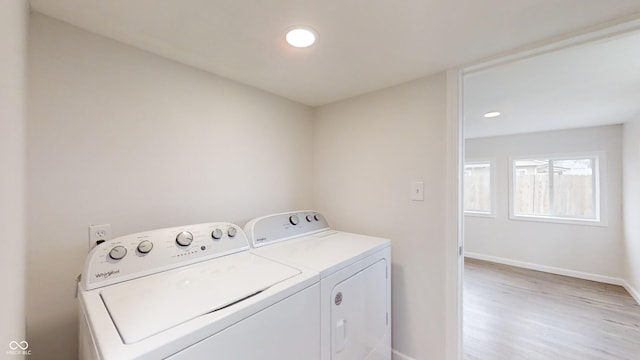 laundry area with washing machine and dryer and light hardwood / wood-style floors