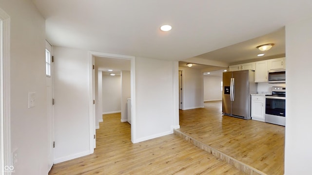 kitchen with white cabinets, light wood-type flooring, and stainless steel appliances