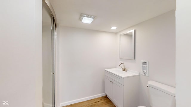 bathroom with wood-type flooring, vanity, toilet, and a shower with shower door