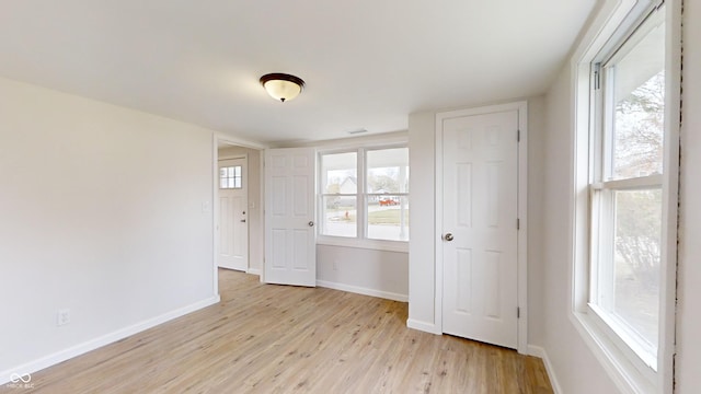 empty room with light hardwood / wood-style flooring and plenty of natural light