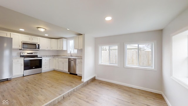 kitchen with appliances with stainless steel finishes, light hardwood / wood-style floors, and white cabinets