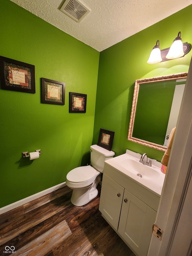 bathroom with hardwood / wood-style floors, vanity, a textured ceiling, and toilet